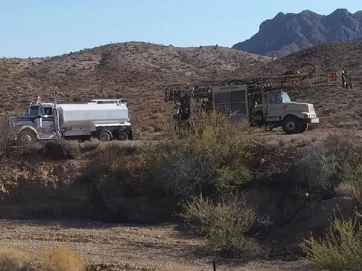A Universal Drilling rig and water truck working a desert parcel below the mountains